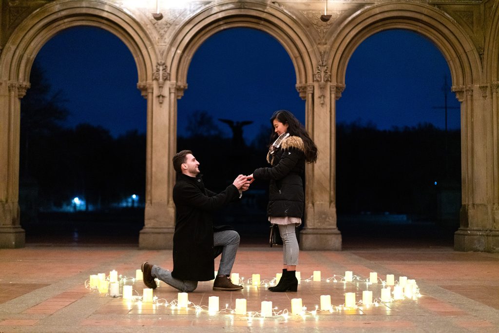 Evening proposal under the arches of Bethesda Terrace, a ring of candles on the stone floor