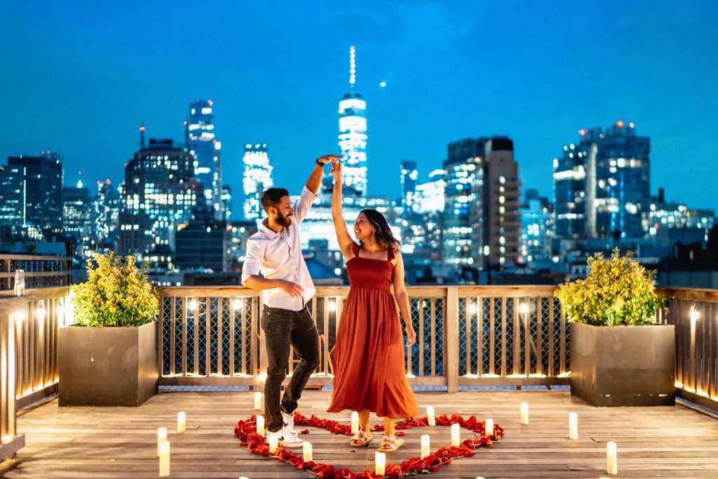 Couple dancing inside a heart of rose petals on a private rooftop, One World Trade Center lit up behind them