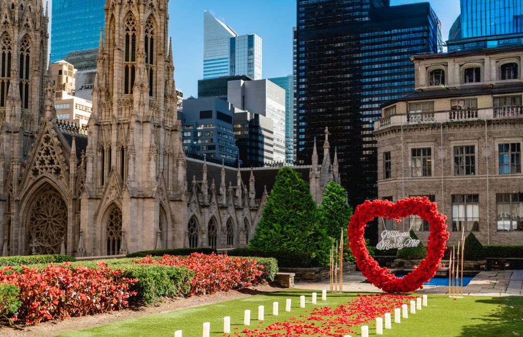 Red rose heart on the lawn at 620 Loft & Garden, the spires of St. Patrick's Cathedral rising behind the hedges