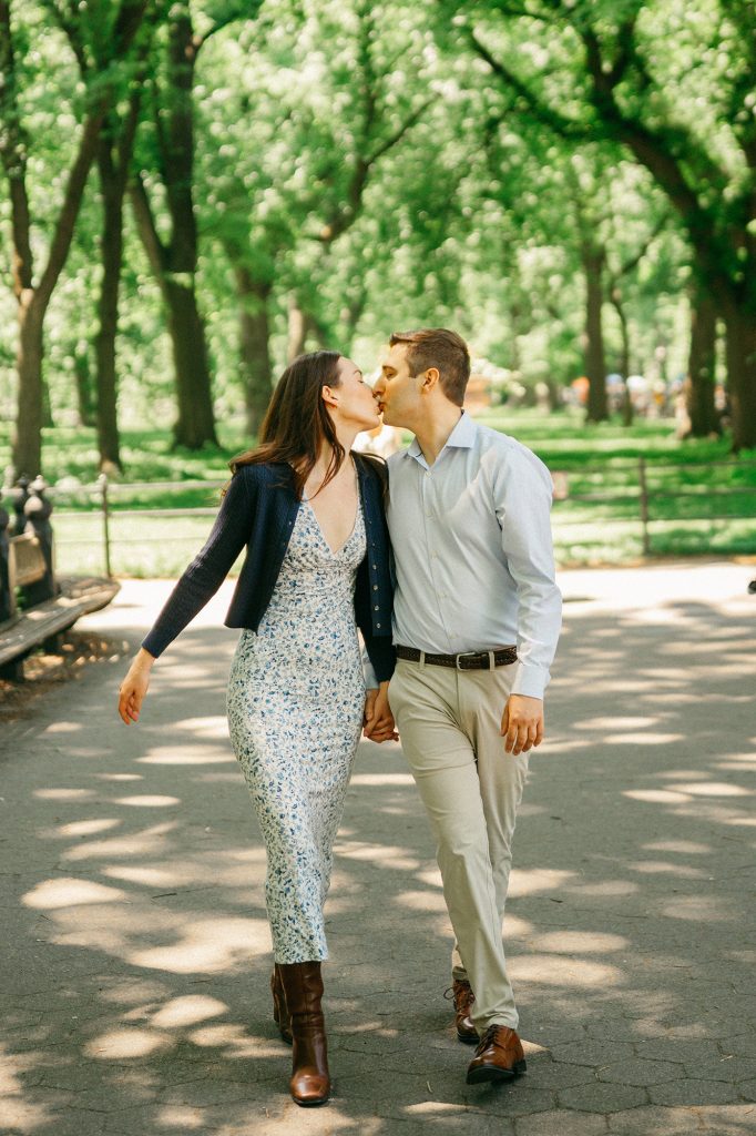 Newly engaged couple kissing as they walk toward the camera on The Mall in Central Park