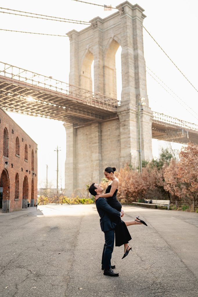 Newly engaged couple under the arches of the Brooklyn Bridge in DUMBO, New York