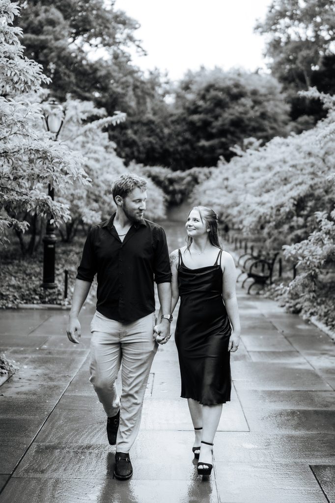 Black and white photograph of a newly engaged couple walking at the Conservatory Garden in spring