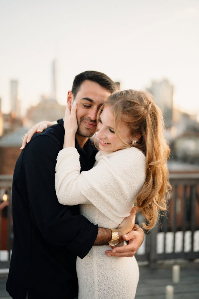 Newly engaged couple embracing in golden hour light on a private rooftop in Manhattan
