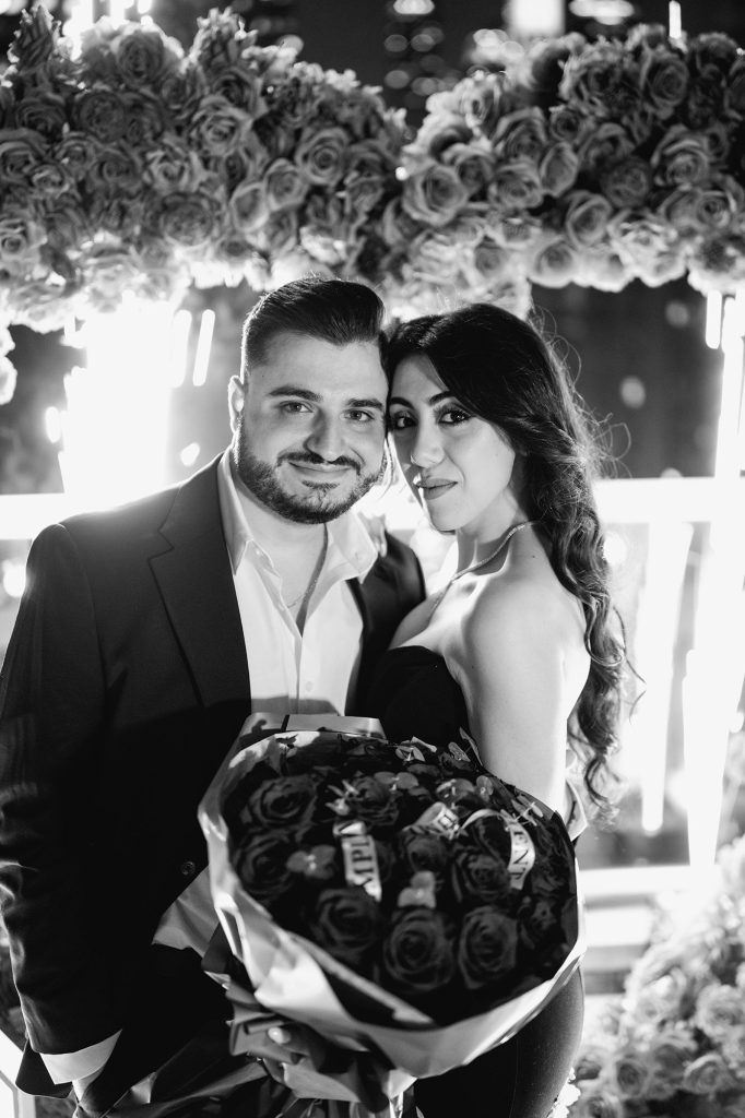 Black and white engagement portrait with a bouquet of roses at Empire State View Rooftop, Manhattan