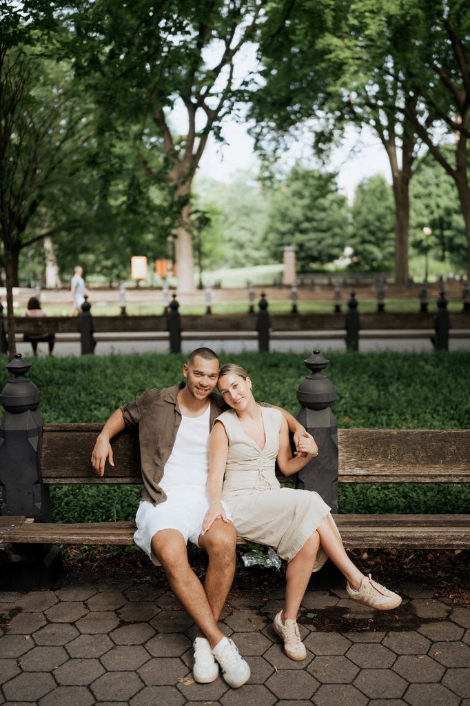 Newly engaged couple on a bench on a tree-lined path in Central Park, New York
