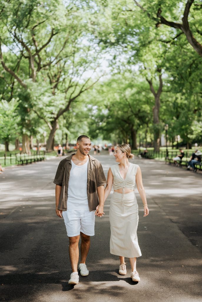 Newly engaged couple walking a tree-lined path in Central Park, New York