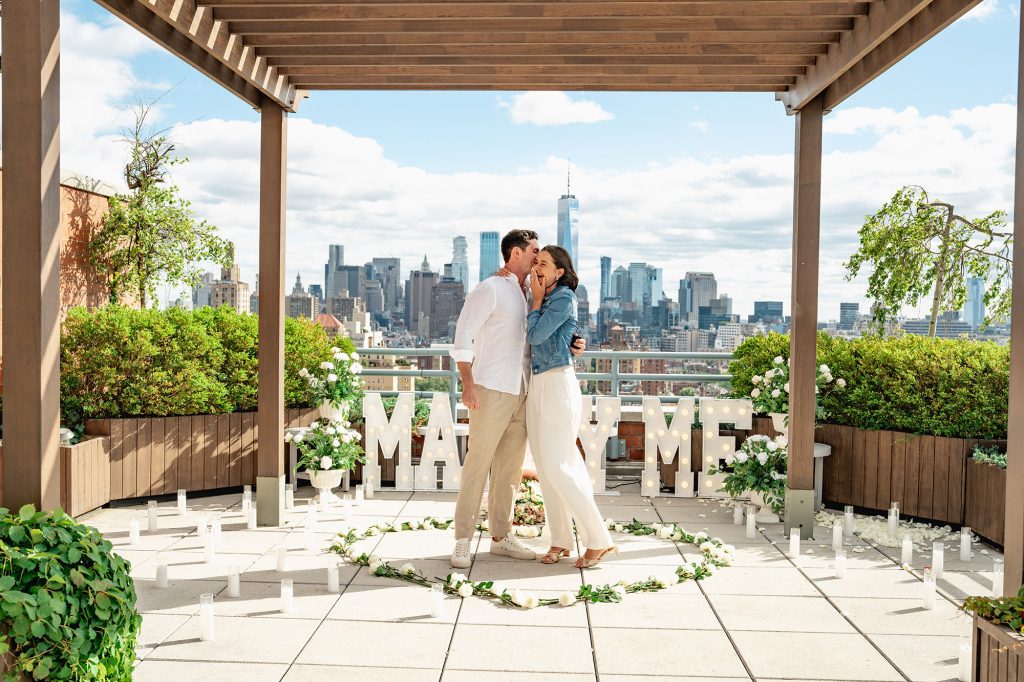 Newly engaged couple under a rooftop pergola in Manhattan with the Downtown skyline behind