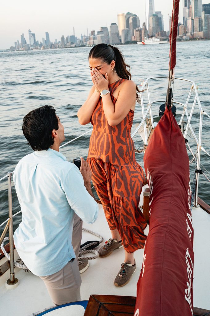 Proposal reaction on a New York yacht, the city skyline behind the boat