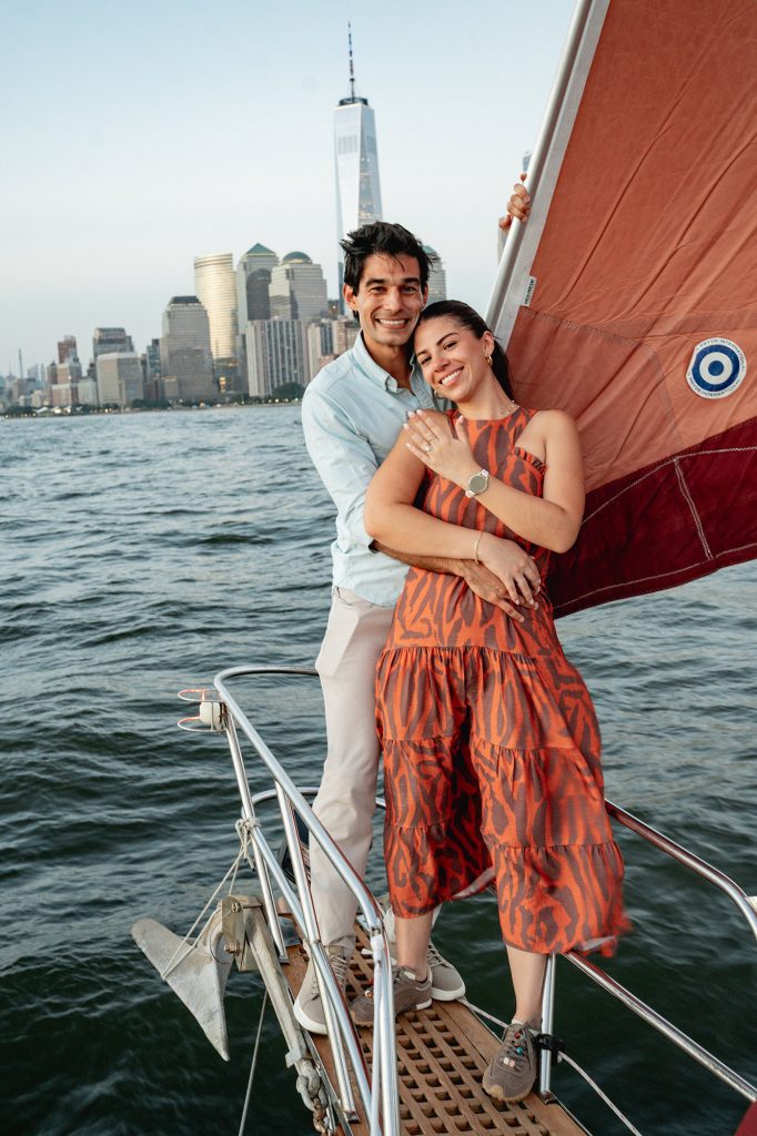 Newly engaged couple on a yacht in New York with the Lower Manhattan skyline behind