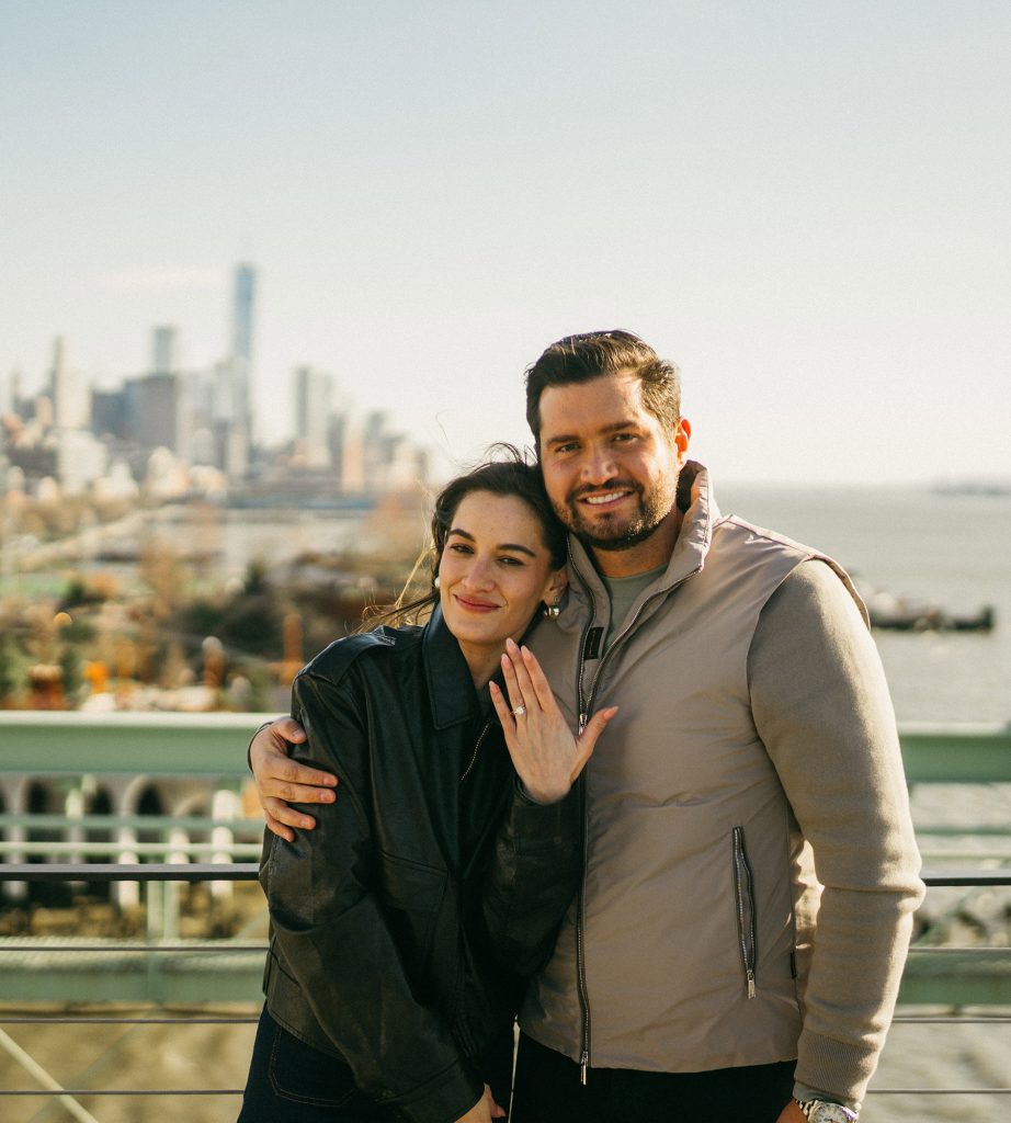 Woman showing her engagement ring at Pier 57, Manhattan, the Downtown skyline behind