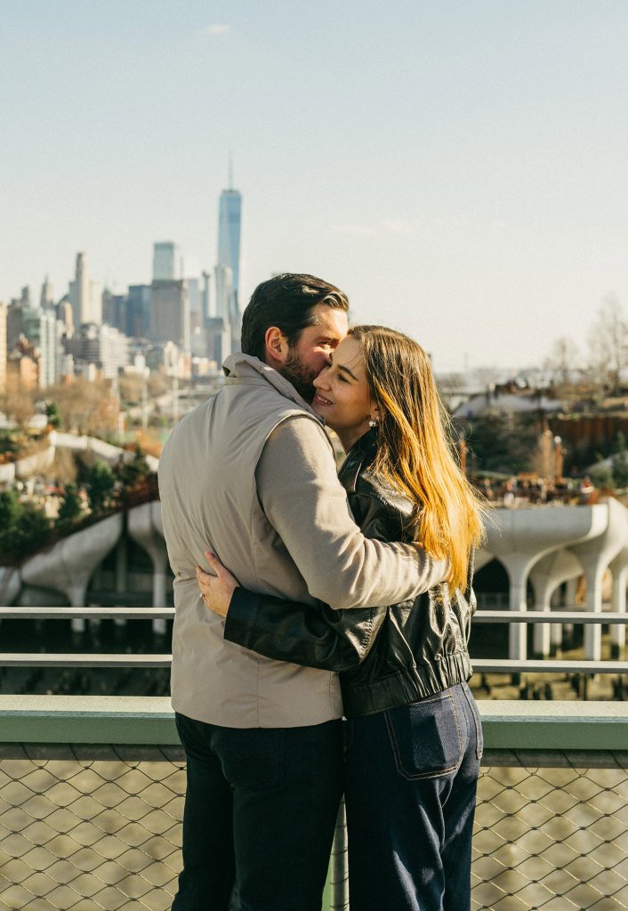 Newly engaged couple at Pier 57 with One World Trade Center across the Hudson River