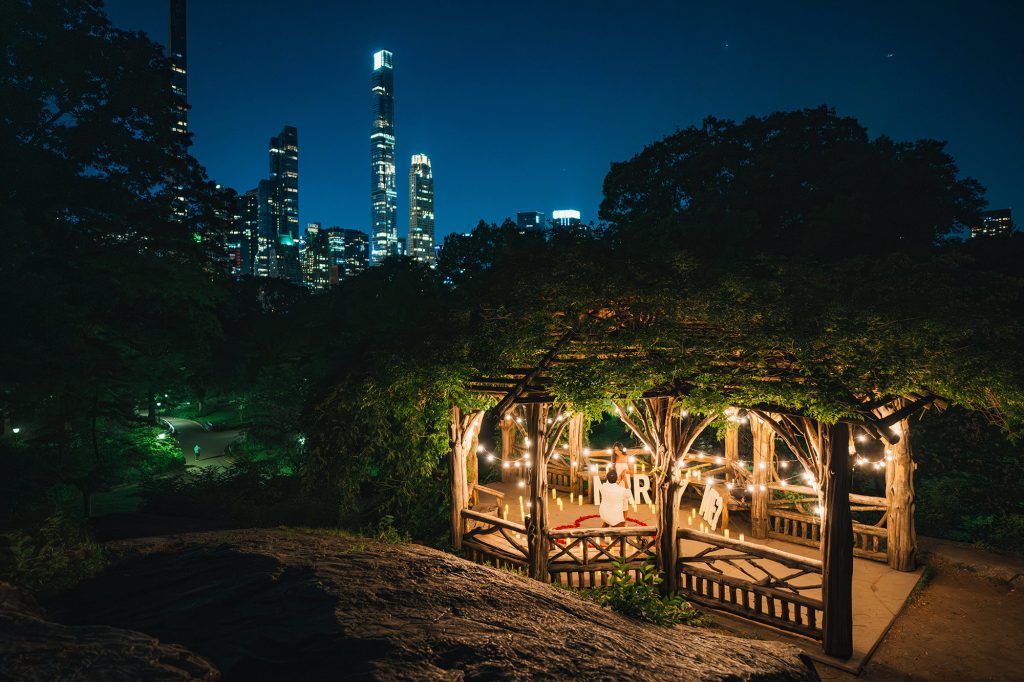 Summerhouse at the Dene, Central Park lit with candles for a surprise proposal, Midtown skyline behind the trees