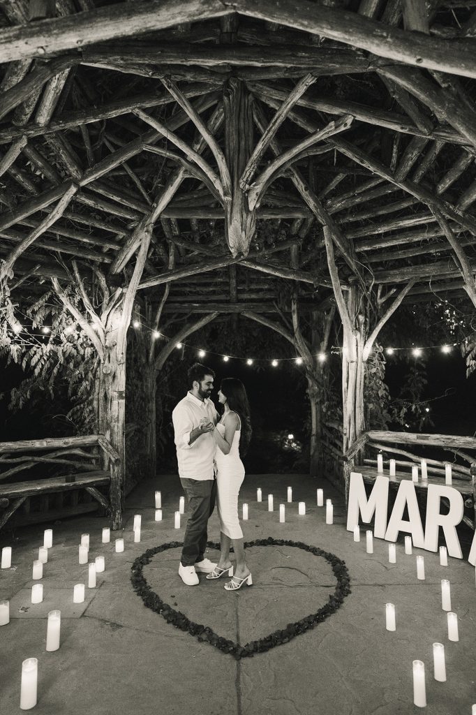 Black and white photograph of a candlelit proposal inside a rose petal heart at Summerhouse at the Dene, Central Park