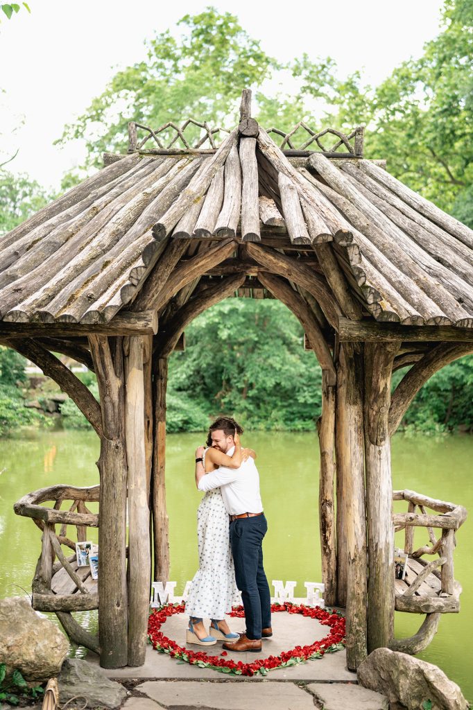 Newly engaged couple embracing inside the rustic shelter at Wagner Cove, Central Park